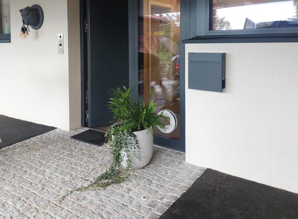 Eine maßgeschneiderte Katzenklappe, professionell eingebaut in das untere Element einer eleganten Haustür.